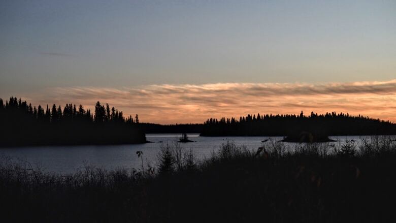 A lake with islands in it is seen with the sunset making the sky orange-red.