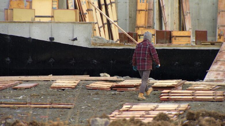 A man in a red sweater walking toward an under construction house. 