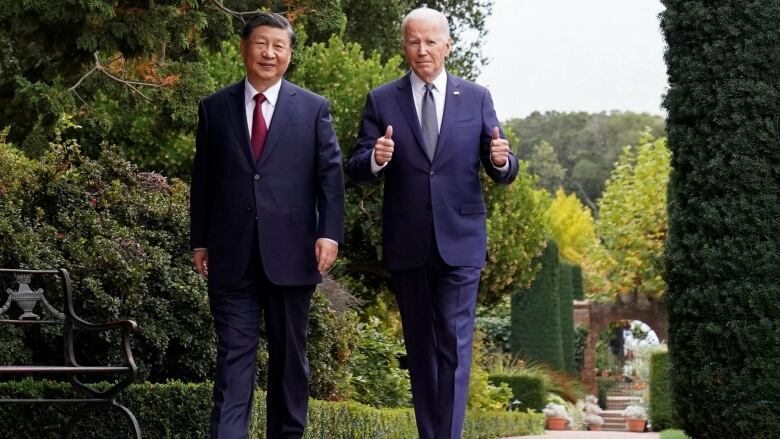 Leaders walking outdoors. Biden offers thumbs up