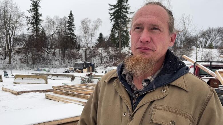 Man with beard stands in front of construction materials