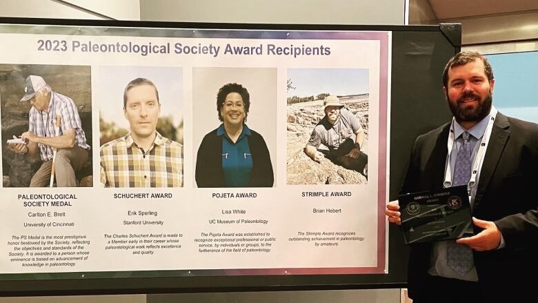 man holding up plaque next to award