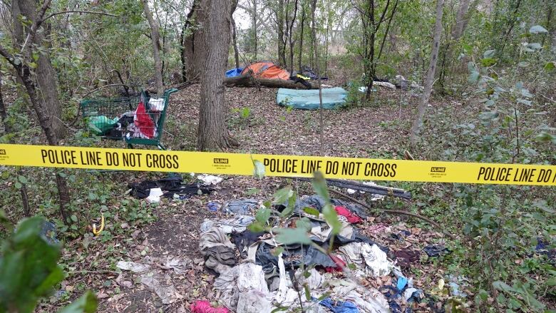 Encampment in wooded area with tents and garbage