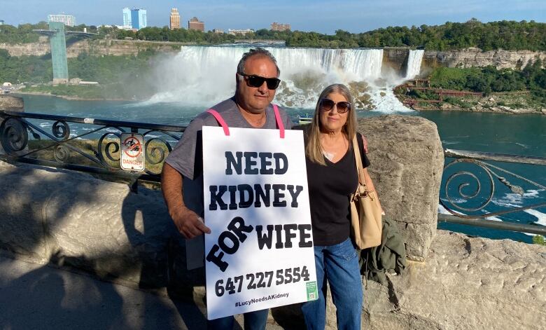 Two people stand in front of Niagara Falls.