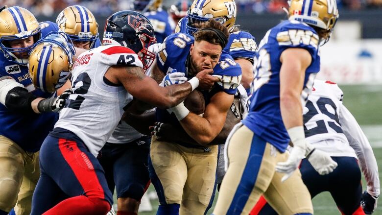 A men's football running back without a helmet runs through a group of players during a game.