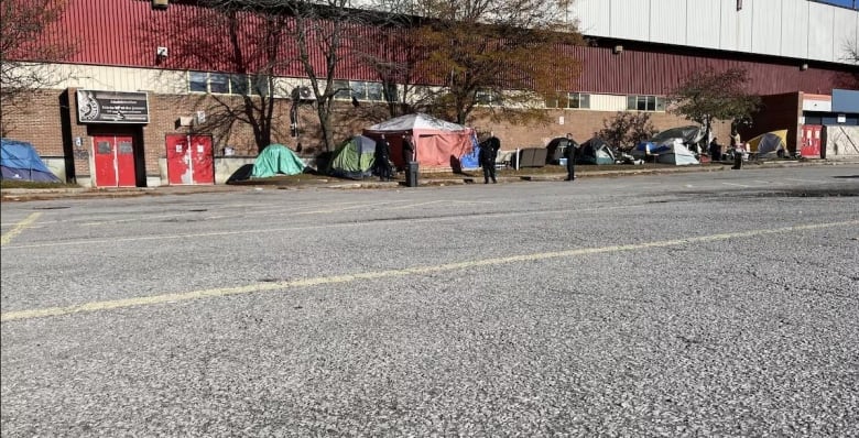 A road with a row of tents in the background.