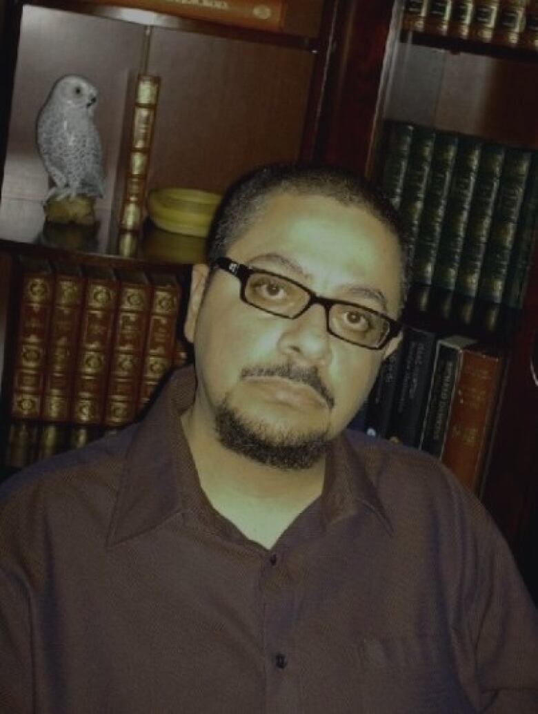 A man in an office with books and a desk.