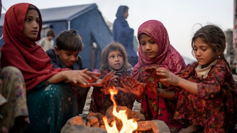 Afghan children huddle around a campfire.