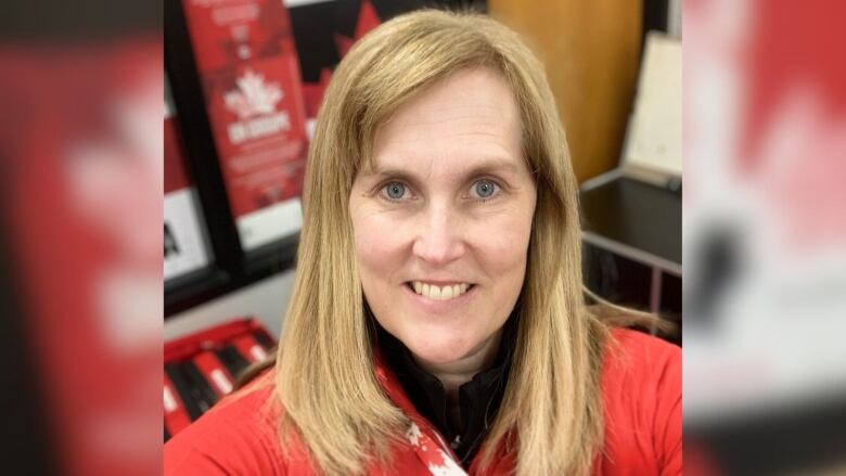 a woman wearing a red sweater smiles and looks at the camera 