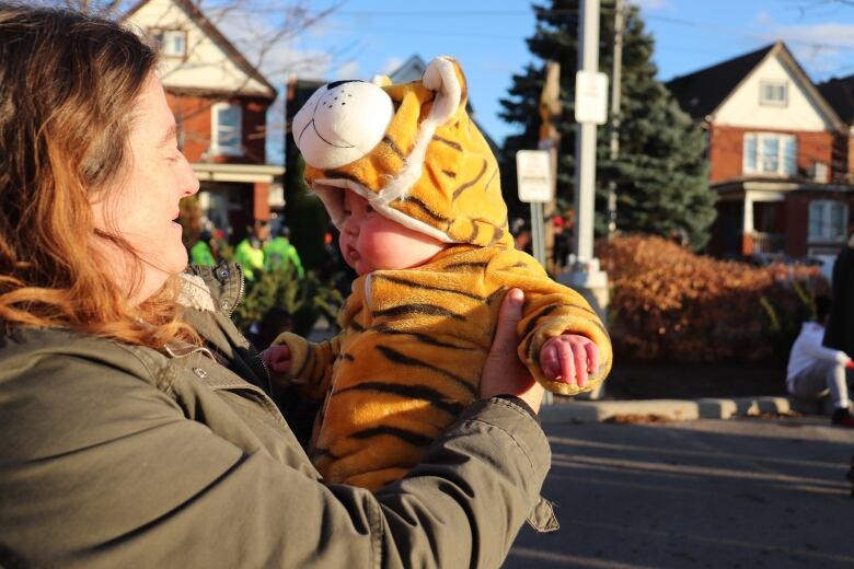 A woman holds a baby wearing a tiger costume.