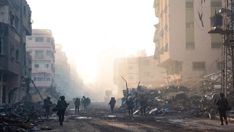 Soldiers walk through rubble