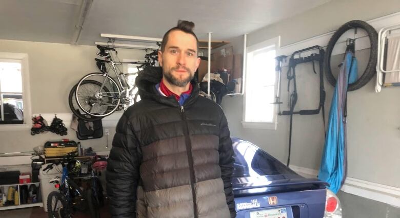 Sbastien Michaud stands in his garage with his blue car