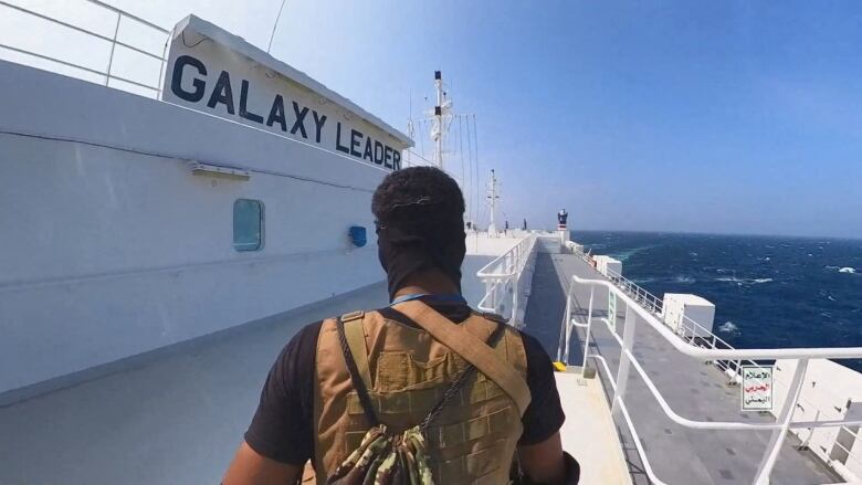 An armed man walks on the deck of cargo ship.