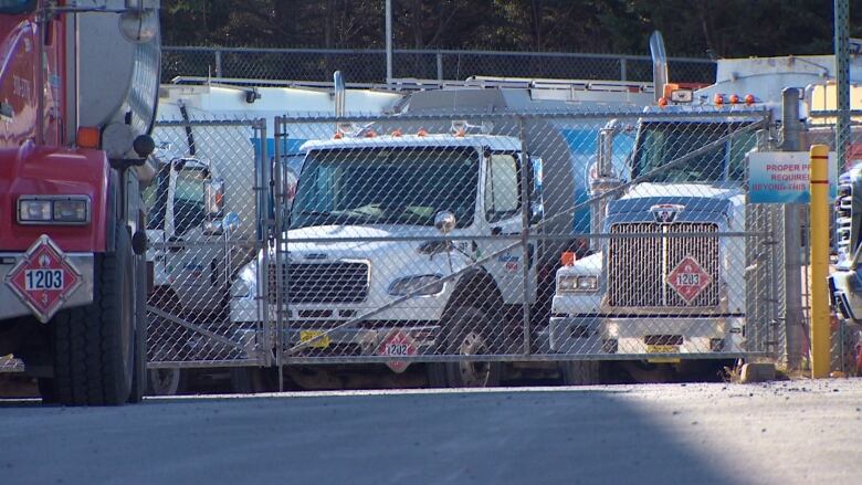 Large trucks parked behind a fence are shown.