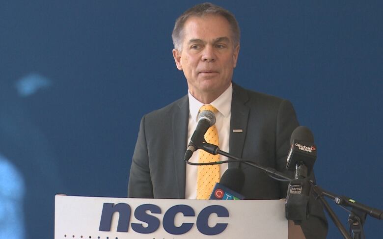 A man in a suit and tie stands at a podium.