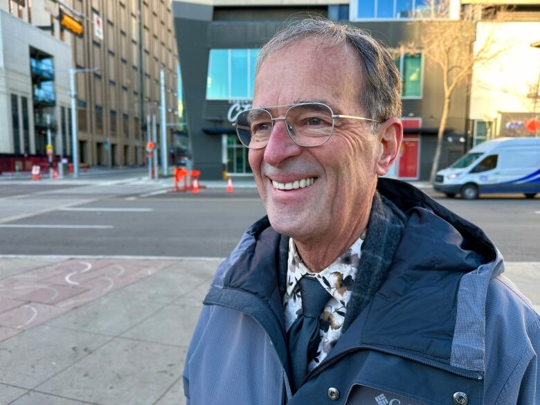 A man wearing a navy jacket smiles.