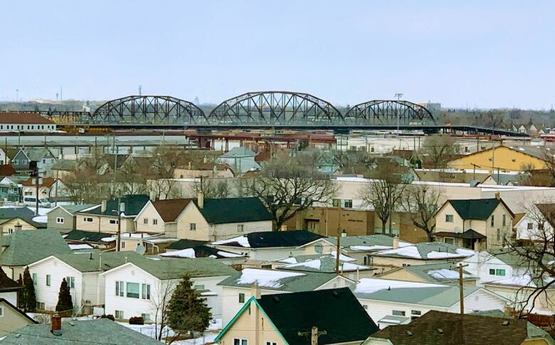 A bridge is seen in the distance beyond the rooftops of houses.