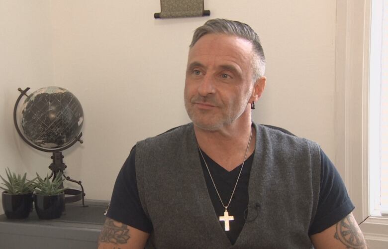 Man wearing a vest and a cross sitting in his office