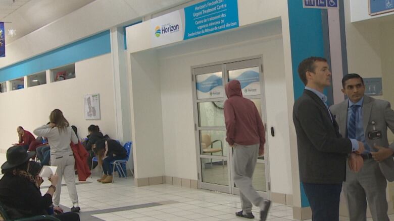 People stand and sit in the hallway of Brookside Mall.