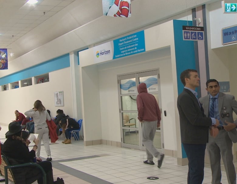 People stand and sit in the hallway of Brookside Mall.