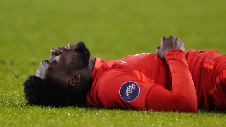 A men's soccer player lays down on his back during a match.