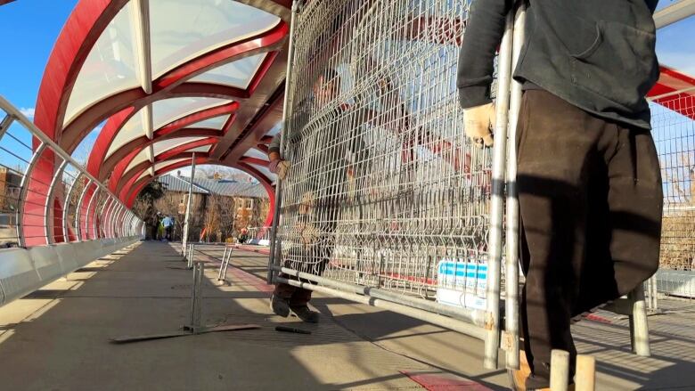 Two men lift a metal fence.