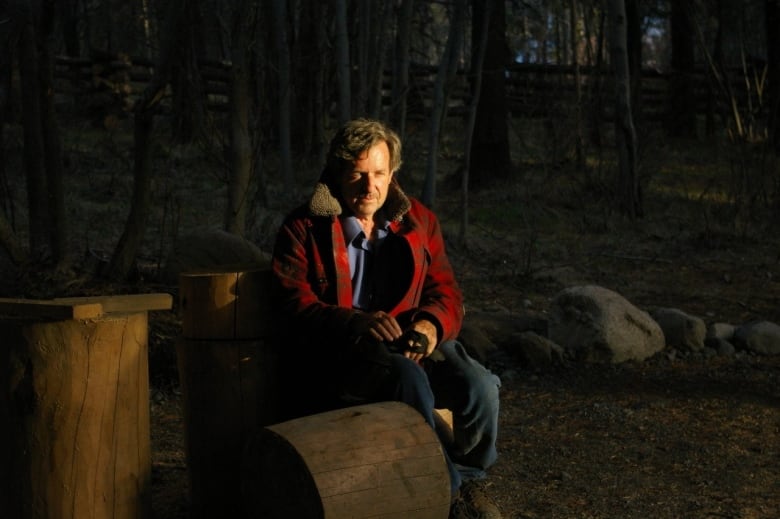 Profile shot of a man in woods wearing red jacket and jeans 