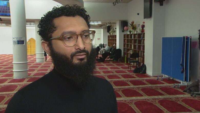 A man with a beard stands in a mosque.