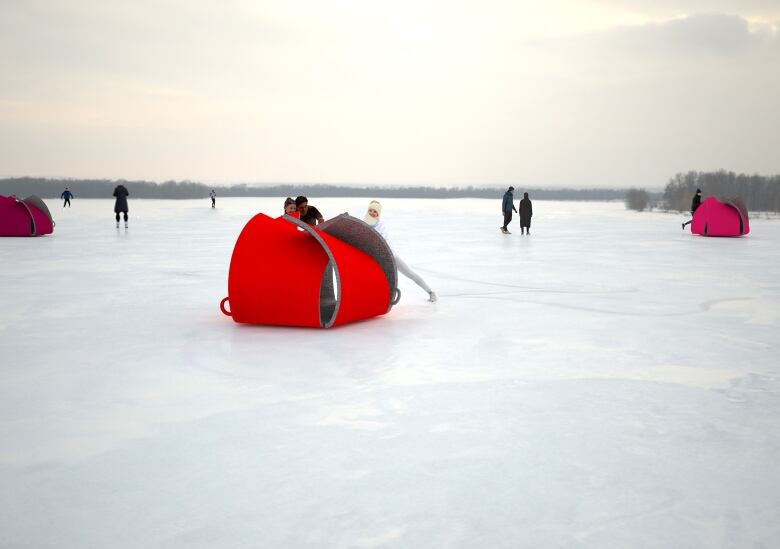 Three small red warming huts along an icy river. 