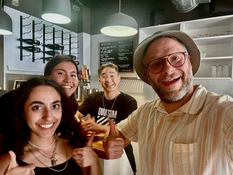 A selfie with four people in frame inside a restaurant.