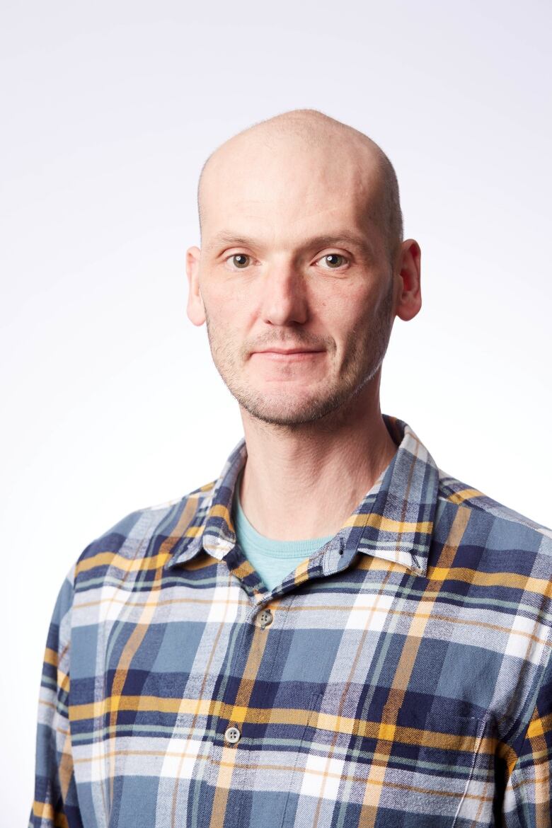 Bald man in plaid shirt with white background.