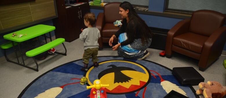 the floor is littered with toys as a child and support worker play 