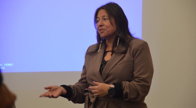 A woman with long dark hair stands in front of a blue lighted square