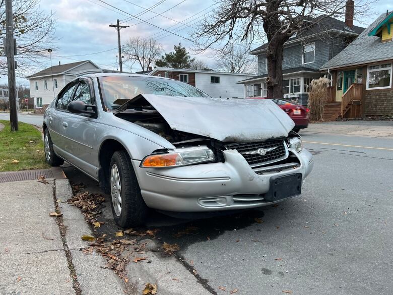 A car is show damaged by the side of the road