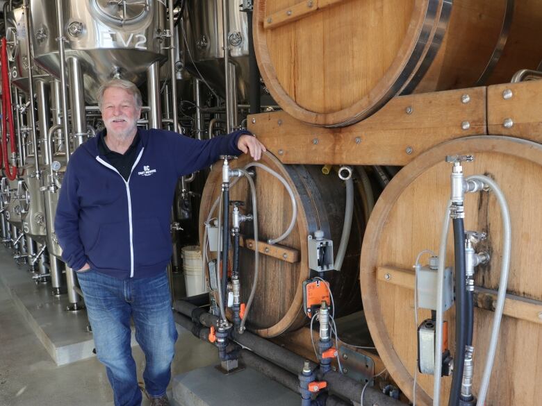 BC Craft Brewers Guild executive director Ken Beattie leans against large kegs of beer. He says craft breweries in the province are struggling to pay their bills and may be forced to close in 2024 when the CEBA deadline arrives.