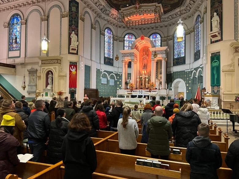 People can be seen standing in church pews for the service.