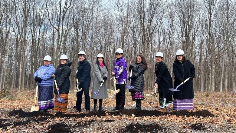 a group of people with shovels and white hardhats breaking ground for a new community centre in Kahnaw:ke.