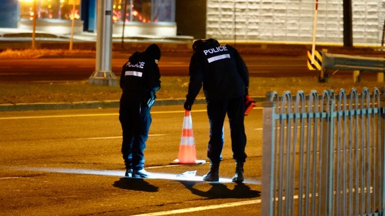 Police officers stand in the street.