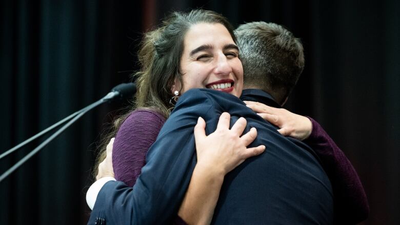 A woman hugs a man.