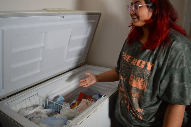 A woman points to inside of freezer