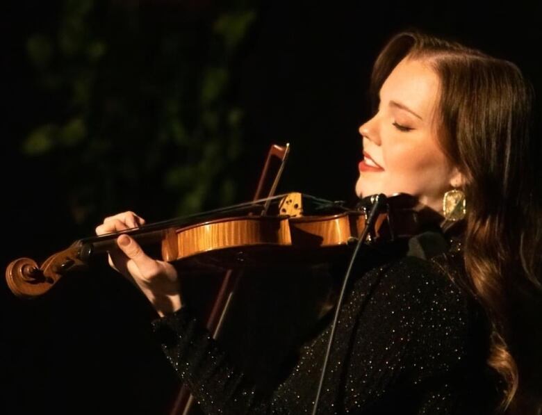 A woman wearing black plays the violin.