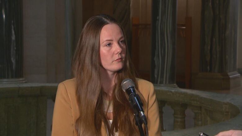 A woman stands at a microphone.