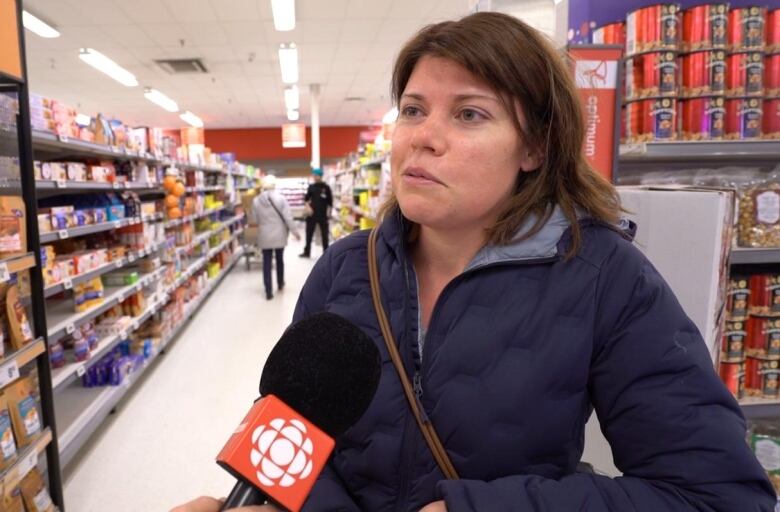 A woman in a grocery store speaks into a CBC microphone.