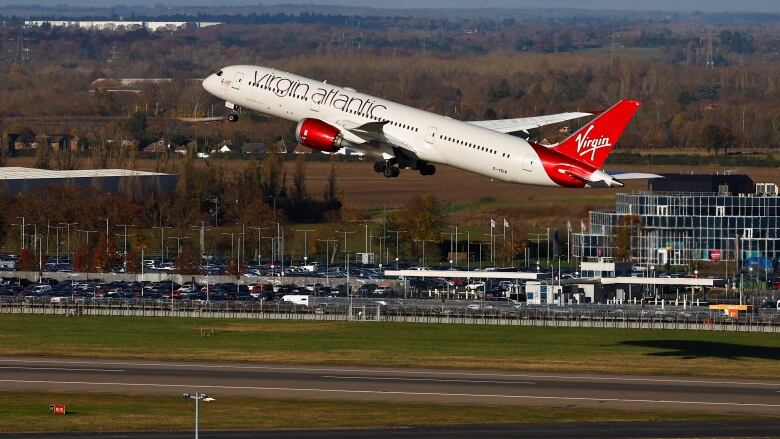 A red and white jetliner takes off from an airport.