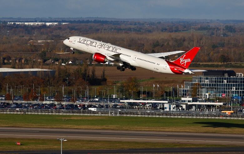 A red and white jetliner takes off from an airport.