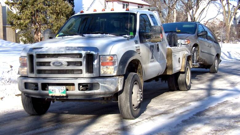 A tow truck tows a van on an icy road.