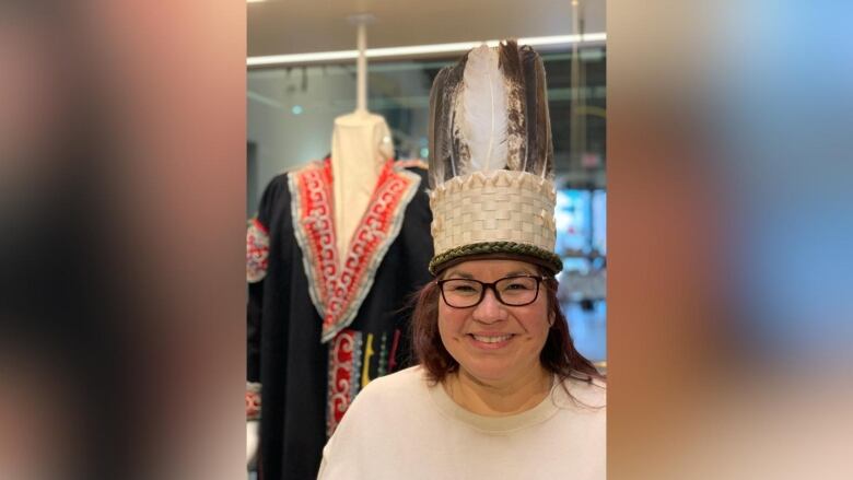 A woman wearing glasses and a woven wooden headdress adorned with feathers.