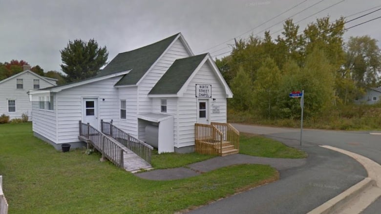 A small white church on a street corner.