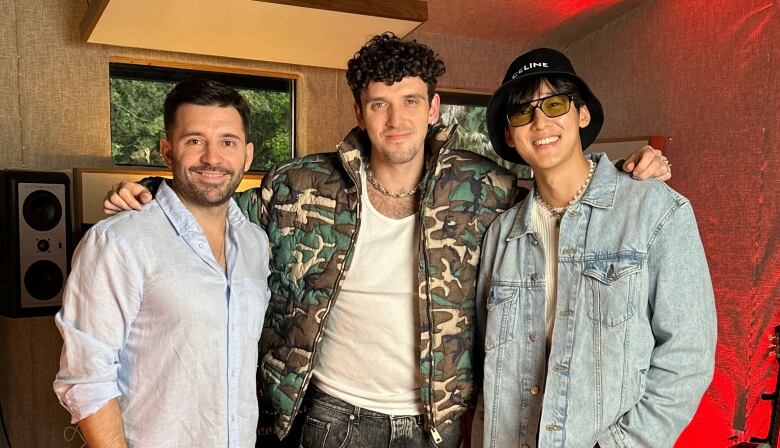 Three men are pictured in a music studio.