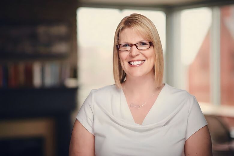 A woman wearing a white shirt smiles for a portrait.