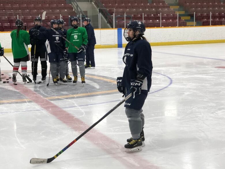 A female hockey player on the ice wearing a dark blue jersey